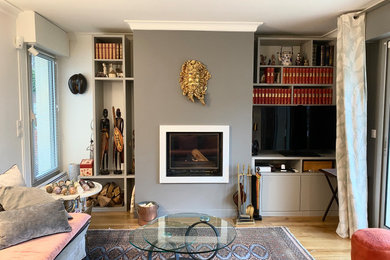Ejemplo de sala de estar con biblioteca cerrada minimalista de tamaño medio sin chimenea y televisor con paredes blancas y suelo de madera clara