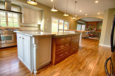 Inspiration for a huge contemporary galley medium tone wood floor eat-in kitchen remodel in St Louis with a double-bowl sink, raised-panel cabinets, white cabinets, marble countertops, white backsplash, ceramic backsplash, black appliances and two islands
