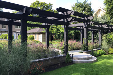Diseño de jardín tradicional en patio trasero con jardín francés y pérgola