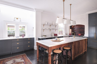 Inspiration for a large traditional l-shaped kitchen pantry in Sydney with a farmhouse sink, flat-panel cabinets, marble benchtops, dark hardwood floors, with island, brown floor and white benchtop.