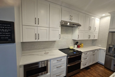 Minimalist dark wood floor kitchen photo in Charlotte with white cabinets, quartzite countertops, white backsplash, stainless steel appliances and white countertops