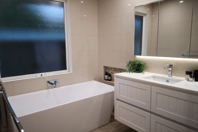 Mid-sized modern master bathroom in Melbourne with recessed-panel cabinets, white cabinets, an alcove tub, a curbless shower, a one-piece toilet, beige tile, cement tile, beige walls, porcelain floors, a drop-in sink, engineered quartz benchtops, beige floor, a hinged shower door and white benchtops.