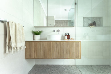 Design ideas for a mid-sized modern bathroom in Sydney with a corner tub, a corner shower, gray tile, a vessel sink, grey floor, a hinged shower door, white benchtops, a niche, a single vanity and a floating vanity.