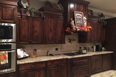 Large elegant ceramic tile eat-in kitchen photo in New Orleans with a double-bowl sink, raised-panel cabinets, dark wood cabinets, granite countertops, beige backsplash, ceramic backsplash, stainless steel appliances and an island