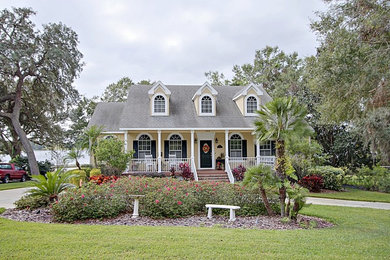 Country two-storey stucco yellow house exterior in Orlando with a gable roof and a shingle roof.