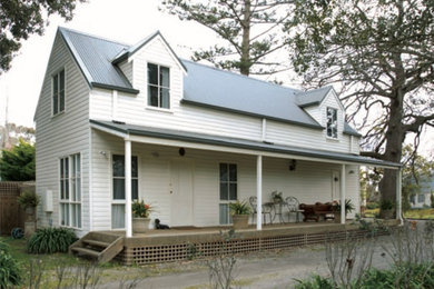Photo of a small country split-level house exterior in Other with wood siding, a gable roof and a metal roof.