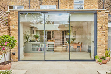 Photo of a large and beige contemporary bungalow brick and rear house exterior in London with a flat roof and a green roof.