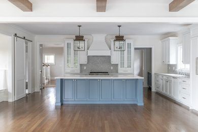 This is an example of a large transitional l-shaped open plan kitchen in New York with glass-front cabinets, white cabinets, quartz benchtops, grey splashback, mosaic tile splashback, panelled appliances, medium hardwood floors, with island, brown floor, white benchtop and an undermount sink.