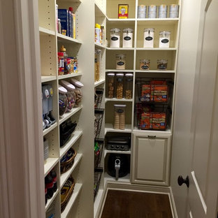 Design ideas for a mid-sized traditional l-shaped kitchen pantry in Cleveland with raised-panel cabinets, white cabinets, dark hardwood floors, no island and brown floor.