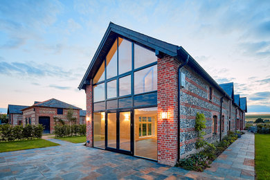 This is an example of a large contemporary two-storey townhouse exterior in Wiltshire with a gable roof and a tile roof.