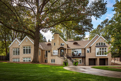 Example of a trendy beige two-story stucco exterior home design in Omaha with a tile roof and a brown roof
