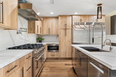 Example of a trendy l-shaped medium tone wood floor and brown floor kitchen design in Phoenix with an undermount sink, flat-panel cabinets, light wood cabinets, white backsplash, stone slab backsplash, stainless steel appliances, an island and white countertops