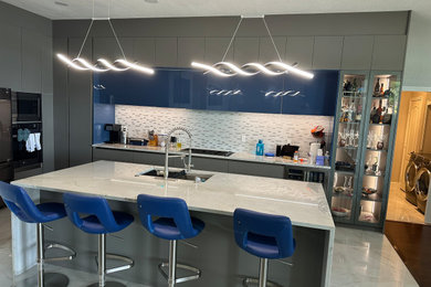 Eat-in kitchen - large modern ceramic tile and gray floor eat-in kitchen idea in Dallas with an undermount sink, flat-panel cabinets, gray cabinets, quartzite countertops, white backsplash, glass tile backsplash, stainless steel appliances, an island and gray countertops