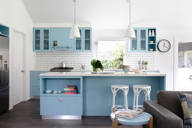Beach style single-wall open plan kitchen in Melbourne with blue cabinets, quartz benchtops, white splashback, subway tile splashback, stainless steel appliances, flat-panel cabinets and with island.