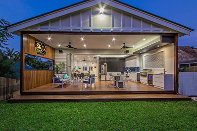 This is an example of a contemporary backyard deck in Brisbane with an outdoor kitchen and a roof extension.