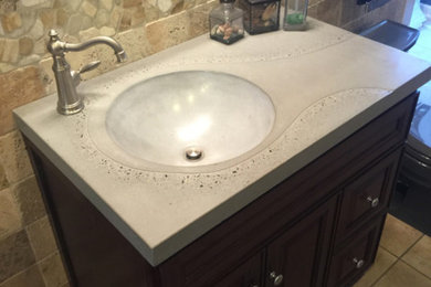 Inspiration for a mid-sized contemporary brown tile and stone tile ceramic tile and beige floor powder room remodel in Philadelphia with recessed-panel cabinets, dark wood cabinets, an integrated sink and concrete countertops