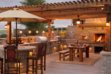 Photo of a mid-sized country backyard patio in Kansas City with an outdoor kitchen, concrete slab and a pergola.