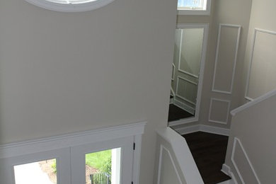 Entryway - contemporary dark wood floor entryway idea in New York with beige walls and a white front door