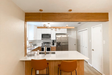 Inspiration for a small scandinavian u-shaped vinyl floor and brown floor eat-in kitchen remodel in Austin with an undermount sink, quartz countertops, white backsplash, porcelain backsplash, stainless steel appliances, a peninsula, white countertops and medium tone wood cabinets