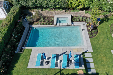 Imagen de piscina natural clásica de tamaño medio rectangular en patio lateral con paisajismo de piscina y adoquines de piedra natural