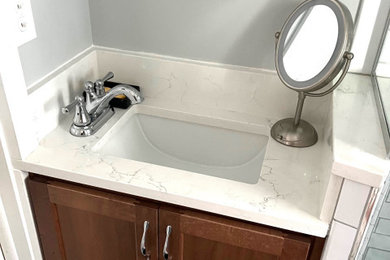 Example of a small classic master white tile and ceramic tile ceramic tile, white floor and single-sink corner shower design in Detroit with shaker cabinets, brown cabinets, a two-piece toilet, gray walls, an undermount sink, quartz countertops, a hinged shower door, white countertops and a built-in vanity