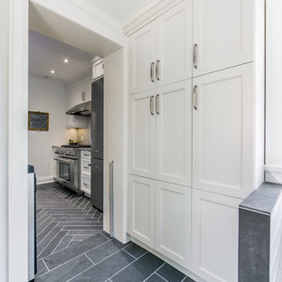 Cette photo montre une arrière-cuisine parallèle chic de taille moyenne avec un placard à porte shaker, des portes de placard blanches, un électroménager en acier inoxydable, un plan de travail en quartz, une péninsule, un évier encastré, une crédence grise, une crédence en carreau de céramique et un sol en ardoise.