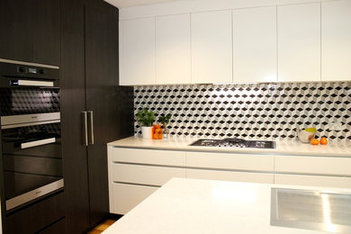 Inspiration for a mid-sized contemporary l-shaped kitchen in Sydney with a drop-in sink, flat-panel cabinets, white cabinets, granite benchtops, stainless steel appliances, medium hardwood floors and with island.