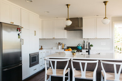 This is an example of a large contemporary l-shaped eat-in kitchen in Seattle with an undermount sink, shaker cabinets, white cabinets, solid surface benchtops, white splashback, mosaic tile splashback, stainless steel appliances, dark hardwood floors, with island and brown floor.