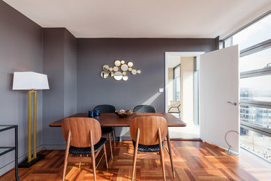 This is an example of a contemporary dining room in Dublin with grey walls, medium hardwood floors, no fireplace and brown floor.