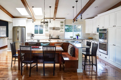 Eat-in kitchen - large transitional l-shaped medium tone wood floor eat-in kitchen idea in Denver with an undermount sink, recessed-panel cabinets, white cabinets, quartz countertops, white backsplash, glass tile backsplash, stainless steel appliances and an island