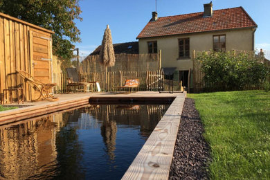 Cette photo montre une grande piscine avant nature avec une terrasse en bois.
