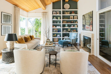 Example of a transitional medium tone wood floor, brown floor and vaulted ceiling living room design in San Francisco with beige walls and a standard fireplace