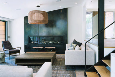 This is an example of a contemporary living room in San Francisco with concrete floors and a metal fireplace surround.