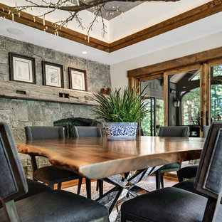 Inspiration for a mid-sized country separate dining room in Other with grey walls, medium hardwood floors, a two-sided fireplace, a stone fireplace surround and brown floor.