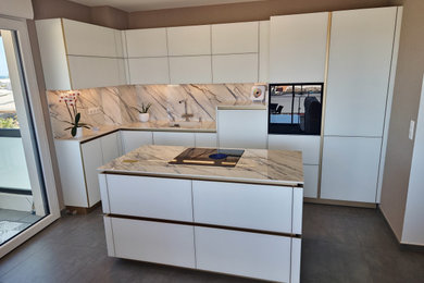 Foto de cocinas en L marinera de tamaño medio abierta con fregadero integrado, puertas de armario blancas, electrodomésticos negros, una isla y suelo gris