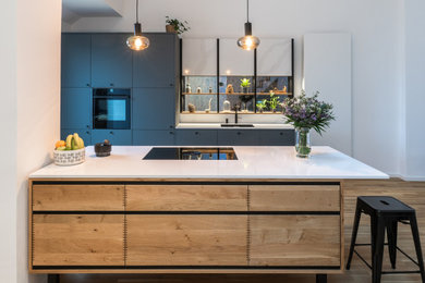 Offene, Zweizeilige, Mittelgroße Urige Küche mit Einbauwaschbecken, schwarzen Elektrogeräten, braunem Holzboden, Kücheninsel und braunem Boden in München