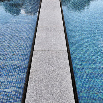 glass tile swimming pool + spa with perimeter overflow + granite decking