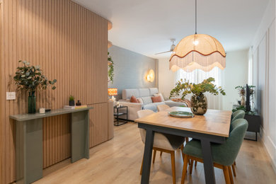Modelo de comedor actual de tamaño medio abierto con paredes blancas, suelo de madera en tonos medios, boiserie y cortinas