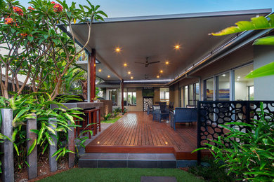Design ideas for a tropical backyard partial sun garden in Sunshine Coast with a fire feature, decking and a wood fence.