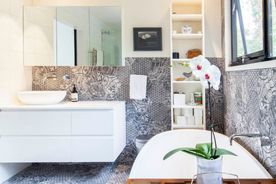 Photo of a large contemporary master bathroom in Melbourne with white cabinets, a freestanding tub, a corner shower, a two-piece toilet, black and white tile, ceramic tile, white walls, ceramic floors, a vessel sink, solid surface benchtops, black floor, a hinged shower door, white benchtops and flat-panel cabinets.
