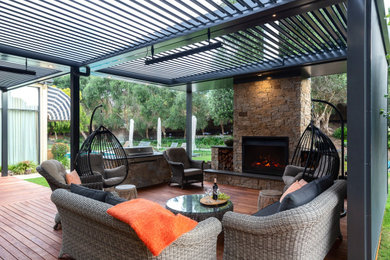 Design ideas for a large contemporary backyard verandah in Melbourne with a fire feature, decking and a pergola.