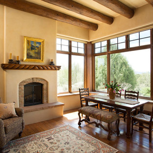 アルバカーキの中サイズのサンタフェスタイルのLDKの画像 (ベージュの壁、無垢フローリング、標準型暖炉、石材の暖炉まわり)