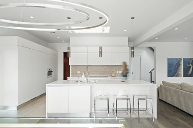 This is an example of a large modern open plan kitchen in New York with a submerged sink, flat-panel cabinets, engineered stone countertops, an island and white worktops.
