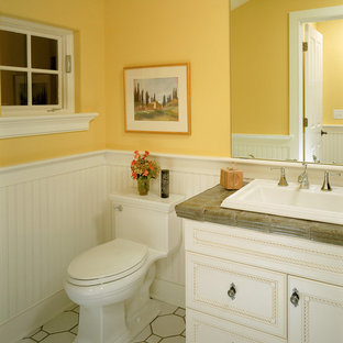 Elegant white floor bathroom photo in New York with a drop-in sink, recessed-panel cabinets, white cabinets, tile countertops, a one-piece toilet and yellow walls