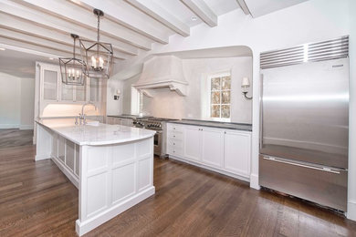 Large transitional l-shaped medium tone wood floor open concept kitchen photo in New York with a farmhouse sink, marble countertops, white backsplash, stainless steel appliances, an island, beaded inset cabinets and white cabinets