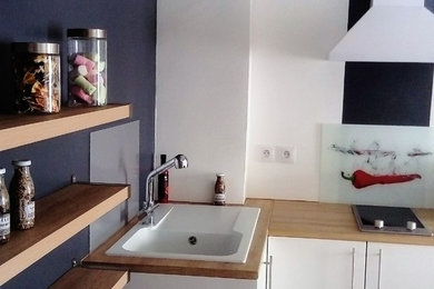 Inspiration pour une petite cuisine ouverte minimaliste en L avec un évier 1 bac, des portes de placard blanches, un plan de travail en stratifié, un électroménager blanc, sol en stratifié, îlot, une crédence multicolore, une crédence en carreau de verre, un sol marron et un plan de travail beige.