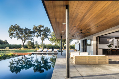 Inspiration for an expansive country backyard rectangular infinity pool in Sacramento with concrete slab.