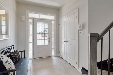 トロントにあるコンテンポラリースタイルのおしゃれな玄関ロビー (ベージュの壁、白いドア、ベージュの床) の写真