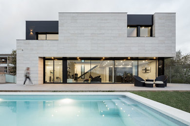 Modelo de fachada de casa minimalista de tamaño medio de dos plantas con revestimiento de piedra y tejado plano