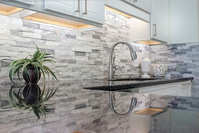 Example of a large transitional l-shaped kitchen design in Other with an undermount sink, recessed-panel cabinets, white cabinets, granite countertops, gray backsplash, stone tile backsplash, stainless steel appliances and a peninsula